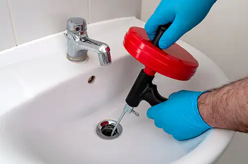 plumber using snake to clear drain